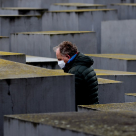 Un hombre con una mascarilla camina entre las estelas del llamado memorial del Holocausto.