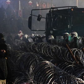 Campamento de refugiados en el paso fronterizo de Bruzgi-Kuznica Bialostocka mientras los militares polacos hacen guardia detrás de una valla cerca de la frontera bielorrusa-polaca, a 15 de noviembre de 2021, en Bruzgi, (Bielorrusia).