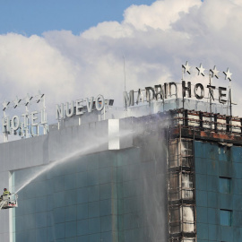 Bomberos extinguen las llamas tras un aparatoso incendio en la fachada exterior del Hotel Nuevo Madrid, situado junto a la zona norte de la M-30 en Madrid, este jueves.