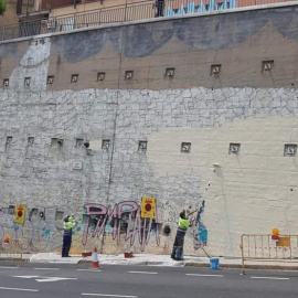 Operaris de BCNeta esborren el mural del tauró capitalista al barri del Carmel.