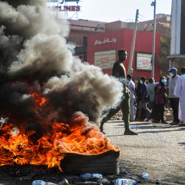 Sudaneses se reúnen cerca de objetos en llamas durante una protesta contra el golpe militar en Jartum.