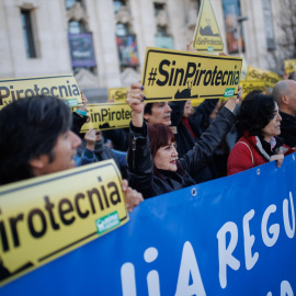 Varias personas protestan con carteles durante una manifestación contra la mascletá programada por el alcalde de Madrid en Madrid Río.