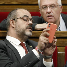 El conseller de Interior de la Generalitat, Miquel Buch (i), y el diputado de JxCat, Josep Maria Forné, en el Parlament de Catalunya. (ANDREU DALMAU | EFE)