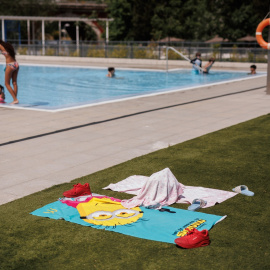 Toallas infantiles en el césped de una piscina el día de apertura de las piscinas públicas, en la piscina del Centro Deportivo Municipal (CDM) José María Cagigal