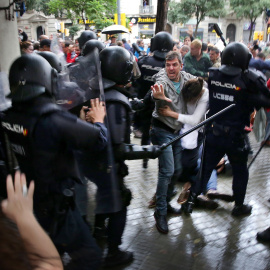 Un home intenta protegir una dona dels cops de porra d'agents antidisturbis de la policia espanyola l'1 d'octubre d'aquest 2017.