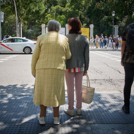 Una mujer mayor espera para cruzar una calle, con ayuda, por el centro de Madrid, a 4 de junio de 2023.