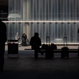 Una persona sentada en un banco junto a su equipaje en el Aeropuerto de Barcelona-El Prat, a 19 de noviembre de 2021.