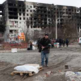 Un hombre recoge sus pertenencias cerca de un bloque de pisos destruido destruido tras un bombardeo en Mariupol.