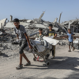 Niños palestinos pasan junto a los restos de edificios destruidos mientras los residentes de Khan Yunis regresan a sus hogares, mayormente devastados por la invasión israelí.