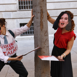 Dos personas con caretas de Almeida y Ayuso fingen talar un árbol durante una manifestación contra la tala de árboles por la ampliación de la L11 de Metro, en la Puerta del Sol, a 8 de octubre de 2023, en Madrid (España).