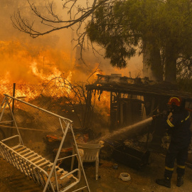 Un bombero combate el fuego en una vivienda al norte de Atenas