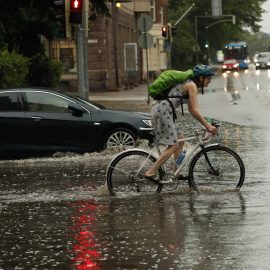 Mujer en bicicleta bajo la lluvia. Foto de archivo.