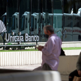 Dos personas en las inmediaciones de la sede de Unicaja Banco en Málaga. E.P./Álex Zea