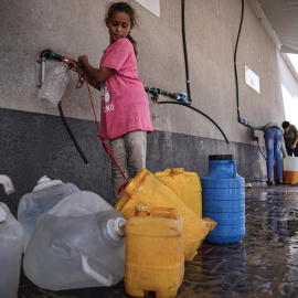 Foto de archivo de una niña palestina llenando garrafas de agua.