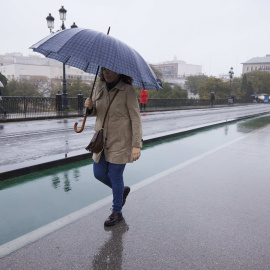 1/4/22-Una señora cruza el puente de Isabel II durante la lluvia caída en la capital andaluza, a 11 de marzo de 2022 en Sevilla.