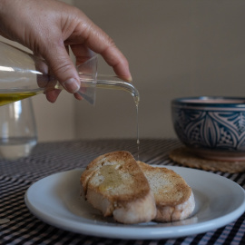 Una persona echa aceite de una aceitera a una tostada en Barcelona, Catalunya (España).