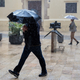 Una persona se protege de la lluvia con un paraguas, esta mañana en València./EFE