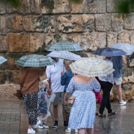 28/08/2024 Transeúntes protegidos con paraguas durante las fuertes lluvias en Sevilla. Foto de archivo.