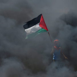 Un chico sostiene una bandera palestina en medio del humo durante las protestas contra el traslado de la embajada de EEUU a Jerusalén. / Reuters