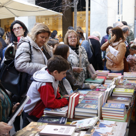 Alguns clients mirant llibres en una parada de la rambla de la Llibertat de Girona durant la diada de Sant Jordi del 2019