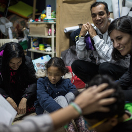 Julio Aponte junto a su mujer Margareth Jiménez (izquierda), juegan con sus hijos y la abogada Patricia Fernández en la habitación de la parroquia San Carlos Borromeo de Entrevías, donde llevan casi cinco meses esperando un plaza en el sistema de asil