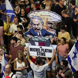 Un manifestante sostiene un cartel con una caricatura del primer ministro israelí, Benjamin Netanyahu, en el que se puede leer "La trampa de Michel Platini", mientras miles de manifestantes que apoyan a las familias de los rehenes israelíes retenidos po