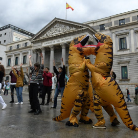 Dos personas disfrazadas de dinosaurios por Ecologistas en Acción, frente al Congreso de los Diputados, a 26 de abril de 2022.