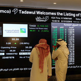 Dos personas observan el panel de la Bolsa de la Riad (Tadawul) los primeros movimientos de Saudi Aramco, tras el estreno bursátil de la petrolera estatal árabe. REUTERS/Ahmed Yosri