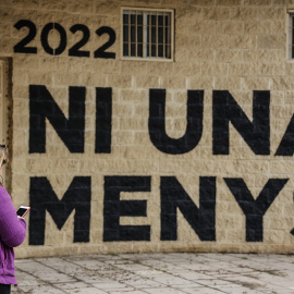 Una mujer pasa por delante de una pared donde se puede leer "Ni una menos" en un acto en memoria de las víctimas de violencia de género y sus hijas e hijos, en el antiguo cauce del Turia, a 8 de marzo de 2022, en Valencia, Comunidad Valenciana