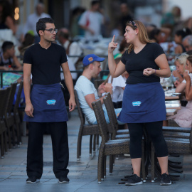 Una camarera conversa con un compañero de trabajo en una terraza de un restaurante en la localidad malagueña de Ronda. REUTERS/Jon Nazca