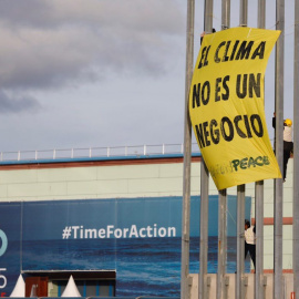 Varios activistas de Greenpeace despliegan una pancarta en una torre de iluminación del recinto ferial IFEMA, en la jornada final de la Cumbre del Clima COP25, este viernes, en Madrid. Los activistas protestan contra la "mercantilización de las negociac