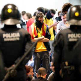 Agentes de los Mossos d'Esquadra controlan a los simpatizantes independentistas que han conseguido entrar en el T1 del Aeropuerto de El Prat tras el anuncio de la plataforma Tsunami Democràtic que ha llamado a paralizar la actividad del aeropuerto, en pr