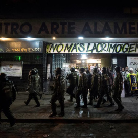 Un grupo de Fuerzas Especiales de Carabineros camina frente al cine Arte Alameda custodiado por voluntarios sanitarios el pasado viernes 13 de diciembre. /EFE