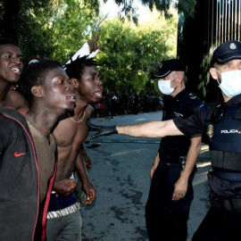 Varios migrantes con dos policias nacionales/EFE