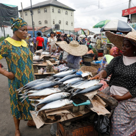 Una mujer habla con una vendedora de pescado en un mercado de Lagos, Nigeria