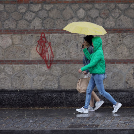 Varias personas caminan con paraguas el día en que han puesto en aviso amarillo a la Comunidad de Madrid por tormentas y lluvias, a 2 de mayo de 2022, en Madrid