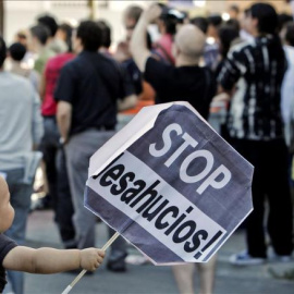 Un niño sujeta un cartel en una concentración contra un desahucio. EFE