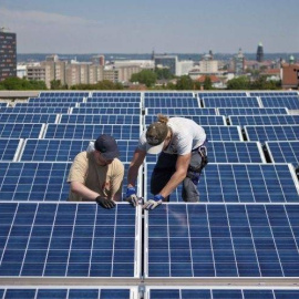 Dos operarios trabajan en las placas solares situadas en la azotea de un edificio. EFE