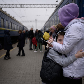 Una mujer abraza a un niño mientras un tren se prepara para salir de la estación principal de trenes en Zaporijia, en el sur de Ucrania, el 17 de abril de 2022.