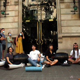 Quatre estudiants asseguts a terra i encadenats davant la delegació del Govern espanyol a Catalunya.