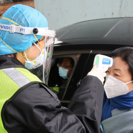 Un oficial de seguridad toma la temperatura a una pasajera tras el brote del coronavirus. REUTERS