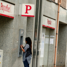 Una foto de junio de 2017 de una mujer utilizando el cajero automático de una oficina del extinto Banco Popular, junto a otra sucursal del Banco Santander. REUTERS/Albert Gea