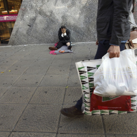 Un sin techo, en la puerta de un centro comercial en temporada de rebajas. REUTERS