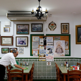 Un camareno limpia una mesa en el restaurante donde trabaja, en Chipiona (Cádiz). REUTERS / Marcelo del Pozo