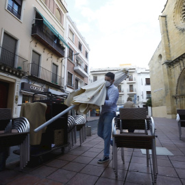 Un trabajador recoge el mobiliario de la terraza de un restaurante en el centro de Córdoba.