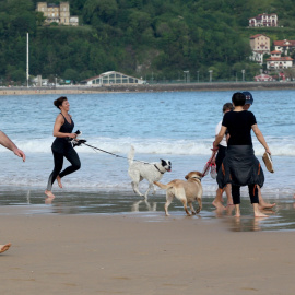 Varias persona caminan y corren con perros en la playa de La Concha en mayo de 2020 (Archivo).