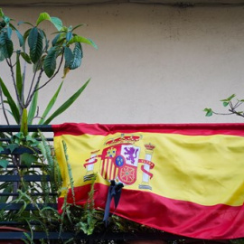 Banderas de España con crespones negros en un balcón.