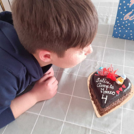 Marco, con 9 años, sopla la vela de la tarta con la celebra con su familia los 4 años como Marco.