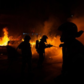 Els Bombers apaguen un foc generat en el transcurs dels aldarulls després de la manfestació per l'empresonament del raper Pablo Hasel a Barcelona.