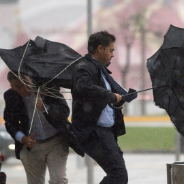 La gente sufriendo el mal tiempo en Málaga y peleándose con sus paraguas./ EFE